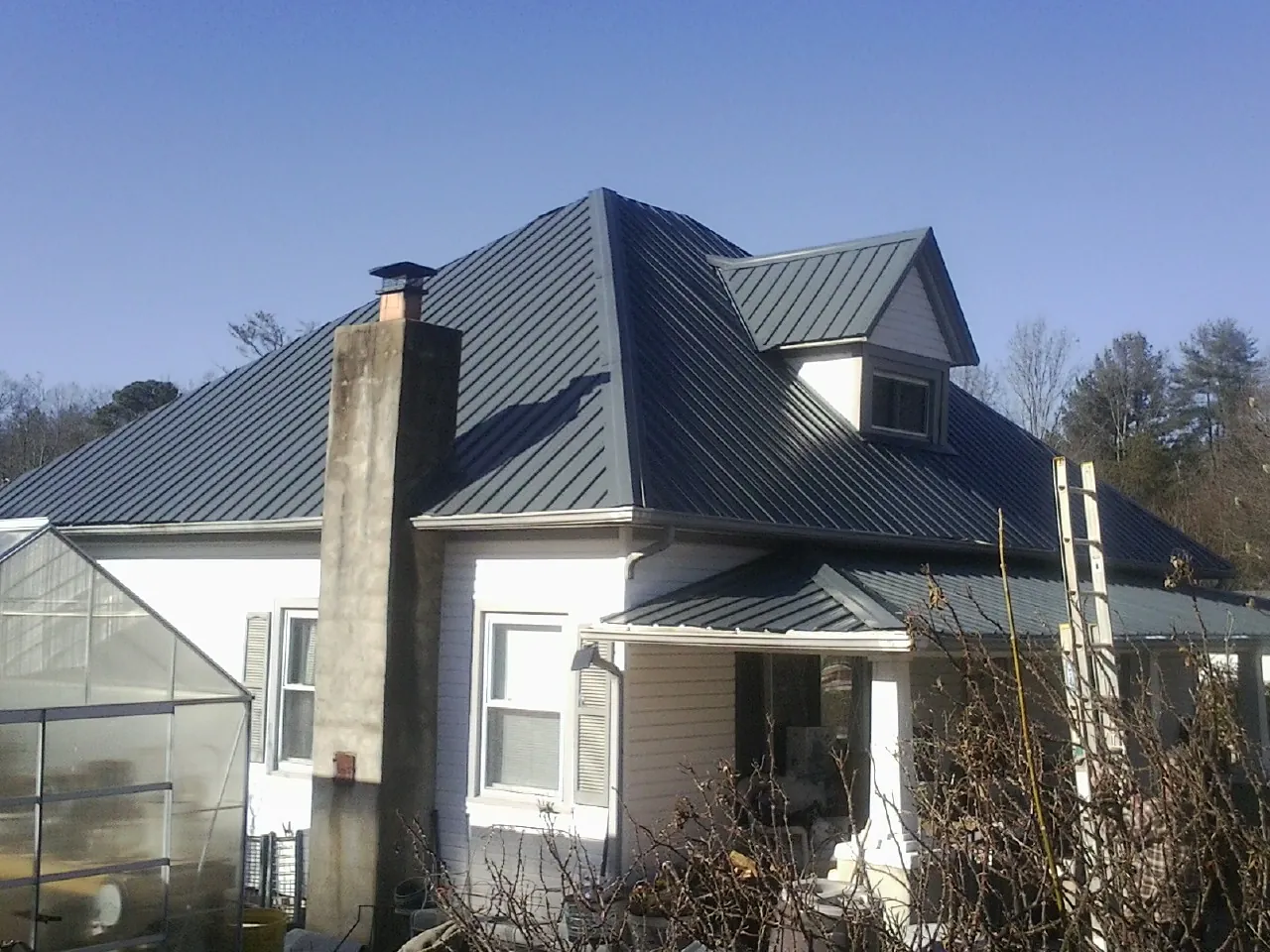 Dark blue standing seam metal roof on a white farmhouse with dormer — Slate & Tile Roof Repair by Roofing Brothers in Broomall