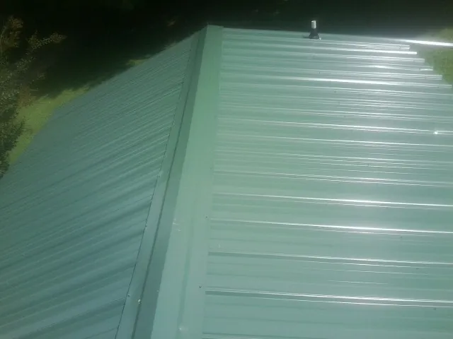 New green metal panels meeting at the ridge of a roof — Flat Roof Repair work by our crew in Broomall