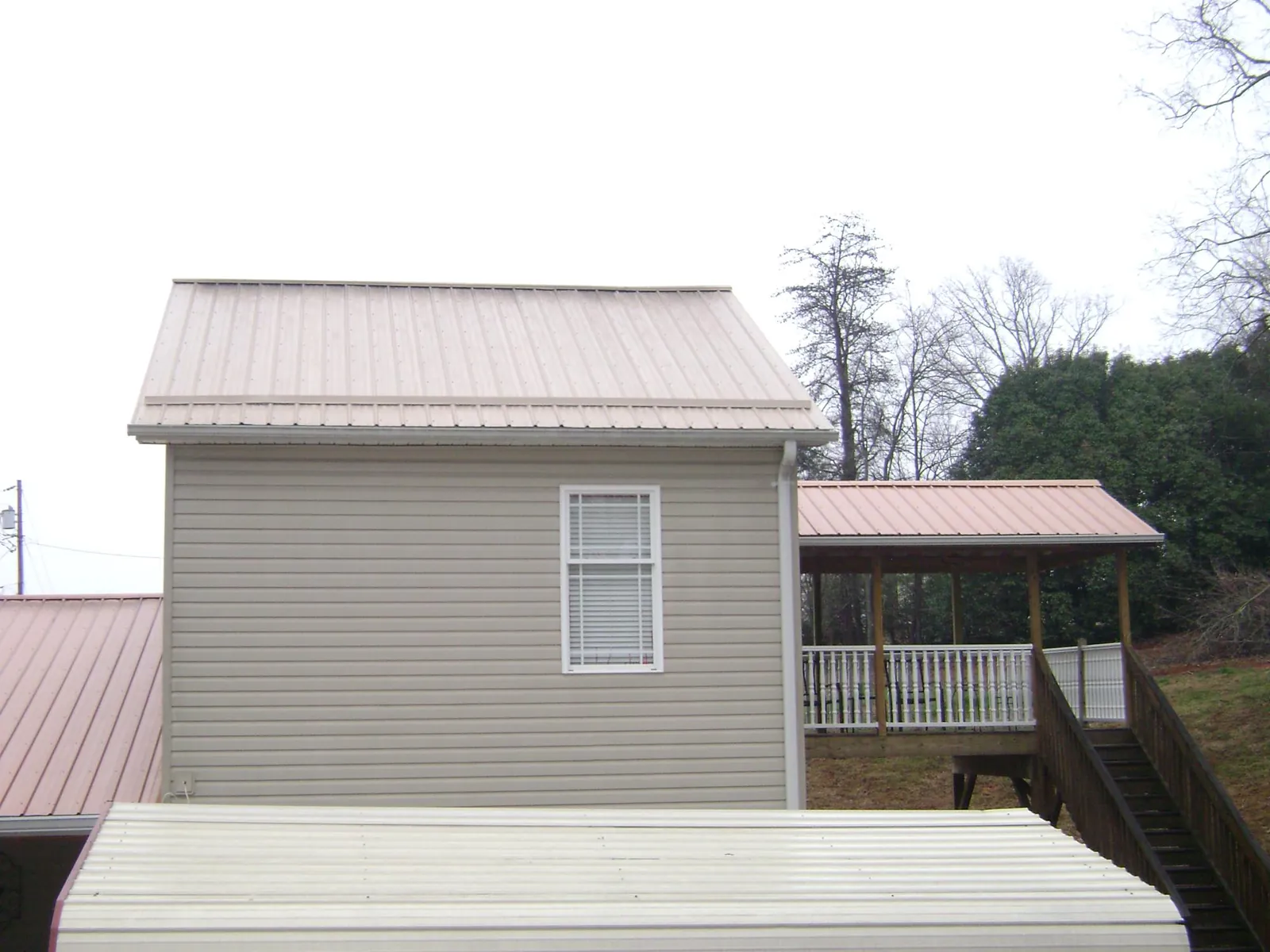 Tan metal roofs on a two story addition and attached porch, from a Roof Replacement job in Broomall