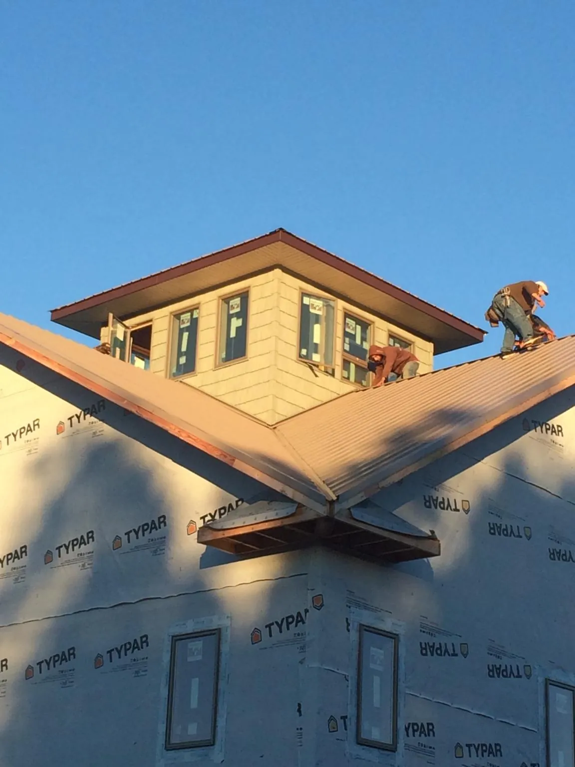 Roofers working around a rooftop cupola on a new metal roof at sunset — Roof Waterproofing in Broomall by Roofing Brothers